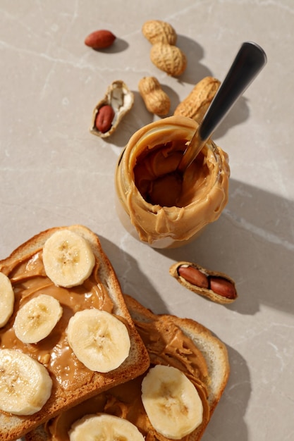 Foto erdnusspaste in einem glaskrug mit toast auf einem hellen hintergrund