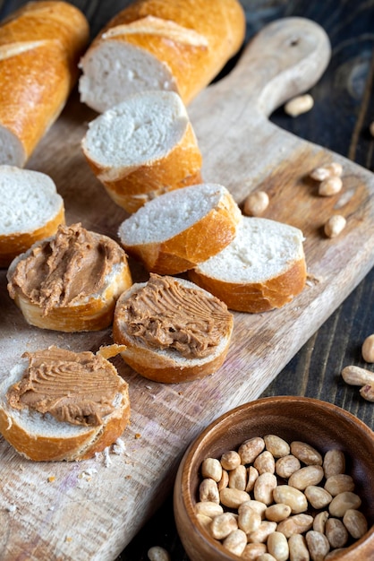 Erdnusspaste mit Erdnussstückchen und weißem Baguette Erdnussbutterfrühstück mit Nussstückchen und Weizenbaguette