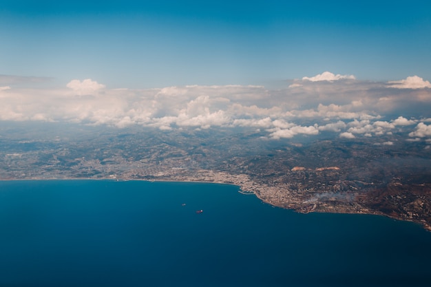 Erdoberfläche, Seeküste und Wolken, Blick aus dem Flugzeug