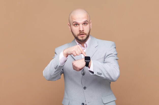 Foto eres un hombre atrasado mirando a la cámara y apuntando a su reloj inteligente