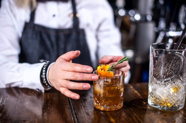 Erfahrene Bardame gießt ein Getränk ein, während sie in der Nähe der Bartheke in der Bar steht