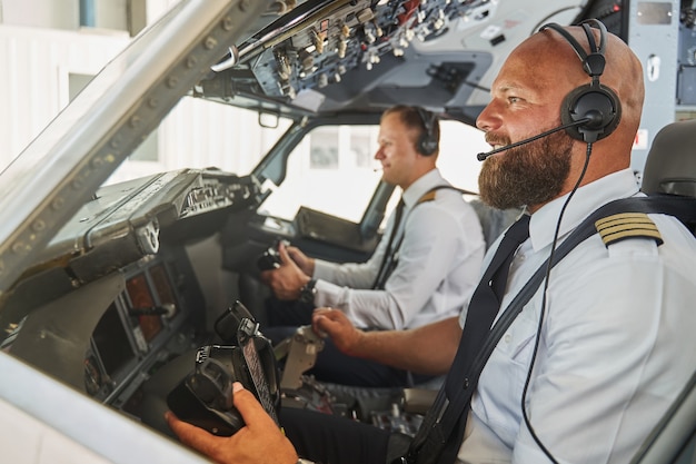 Erfahrene Piloten steuern das Passagierflugzeug aus ihrem Cockpit und lächeln fröhlich