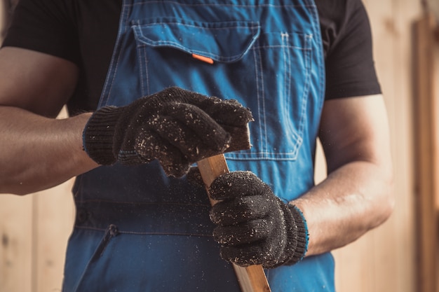 Erfahrener Schreiner in Arbeitskleidung und Kleinunternehmer, der in einer Holzwerkstatt arbeitet