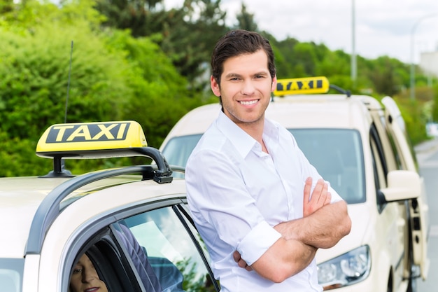 Erfahrener Taxifahrer vor seinem Taxi, der auf einen Passagier wartet