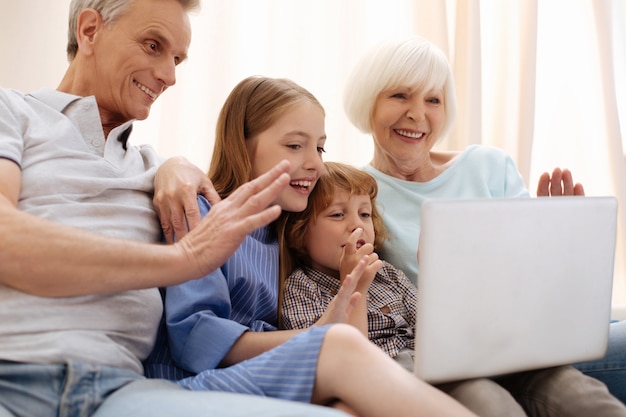 Erfinderische versierte charismatische Geschwister, die mit Mama und Papa sprechen und über ihre schöne Zeit erzählen, während sie ihre Großeltern besuchen