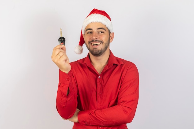 Erfolg Glück Traum dezember Käufer Eigentum Eigentum Kauf Miete Verkauf LKW Autos Konzept Schöner Mann in traditionellem rotem Weihnachtsoutfit und Hut auf dem Kopf, der einen Autoschlüssel hält