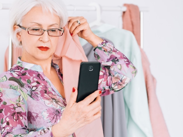 Erfolgreiche ältere Frau. Geschäft mit Modeboutiquen. Ältere Dame, die bei der Analyse des Farbtyps ein Selfie macht.