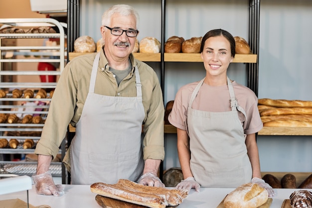 Erfolgreiche Bäcker in Arbeitskleidung stehen am Arbeitsplatz