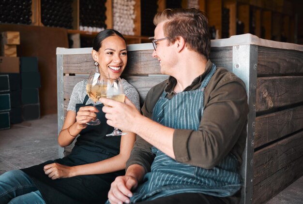 Erfolgreiche Brennereibesitzer entspannen und feiern bei einem Glas Wein im Keller oder Lager Entspannte Winzer oder Mitarbeiter genießen gemeinsam ein alkoholisches Getränk bei der Arbeit