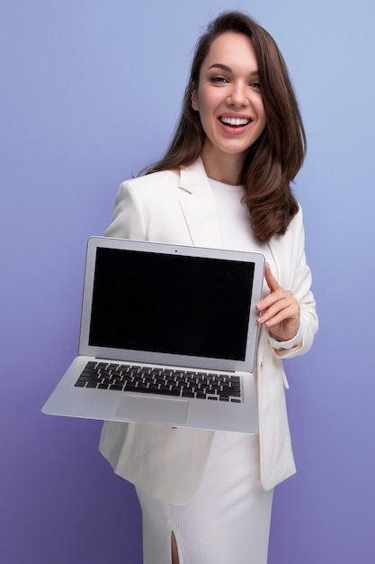 Erfolgreiche brünette Geschäftsfrau im weißen Kleid hält Laptop nach vorne