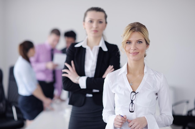 Erfolgreiche Geschäftsfrau, die mit ihren Mitarbeitern im Hintergrund in einem modernen, hellen Büro steht