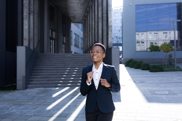 Erfolgreiche Geschäftsfrau freut sich und tanzt vor Vergnügen Afroamerikanerin geht in der Nähe des Büros spazieren