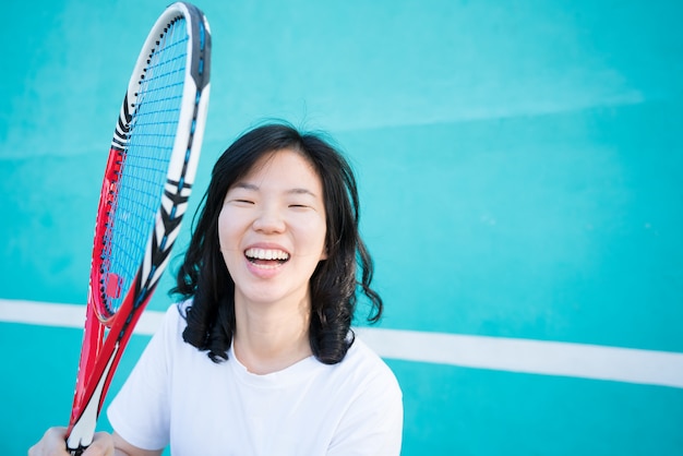 Erfolgreiche glückliche Sportlerin mit Schläger am Tennisplatz. Gesunder Lebensstil.