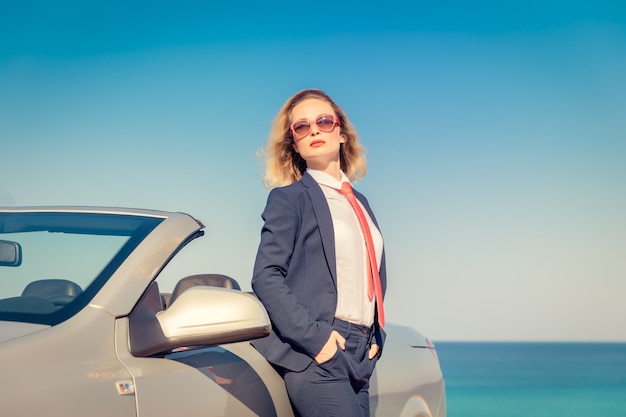 Erfolgreiche junge Geschäftsfrau am Strand Frau sitzt im Cabrio-Oldtimer