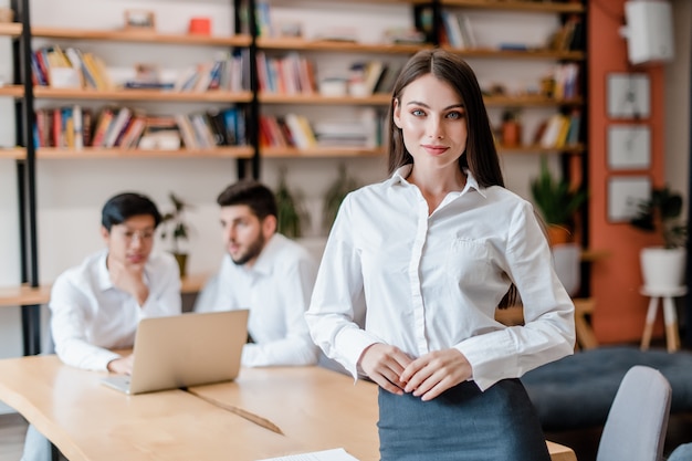 Erfolgreiche junge Geschäftsfrau, die im Firmenbüro mit verschiedenen Arbeitskräften arbeitet