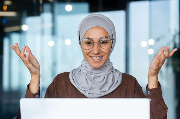 Erfolgreiche und glückliche Frau im Büro am Arbeitsplatz Geschäftsfrau Chefin im Hijab spricht auf Video