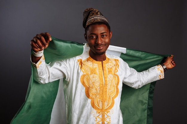 Erfolgreicher afrikanischer Sieger vor dem Schwenken der nigerianischen Flagge Lächelnd und mit Blick auf die Kamera