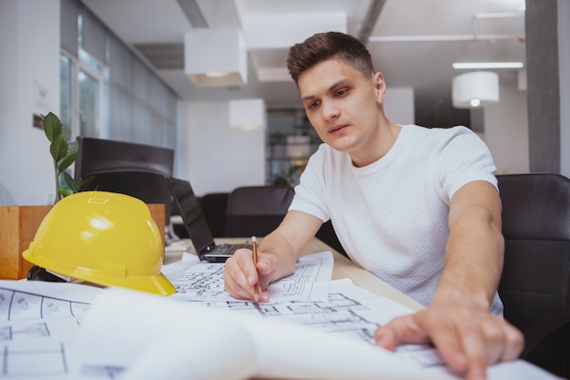 Erfolgreicher Architekt, der an Plänen im Büro arbeitet