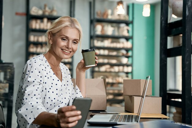 Erfolgreicher Geschäftsinhaber schöne und glückliche Geschäftsfrau, die Kaffee mit Smartphone trinkt und