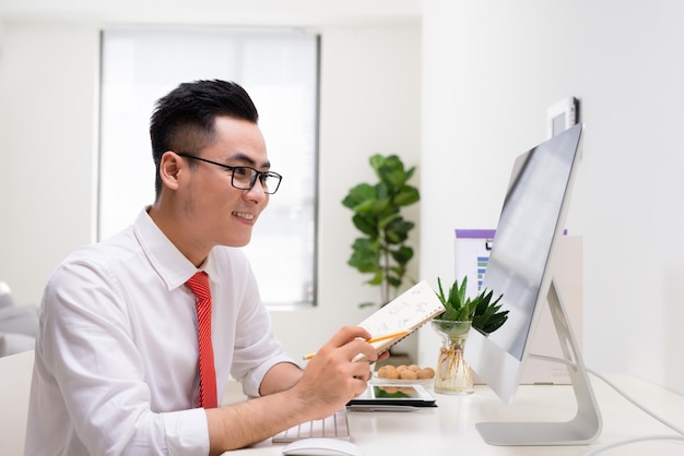 Erfolgreicher Geschäftsmann, der mit Computer im Büro arbeitet