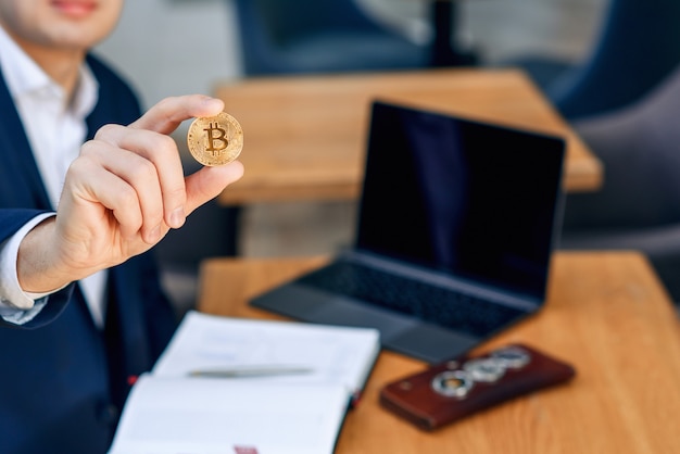 Foto erfolgreicher geschäftsmann hält eine goldene bitcoin-münze in der hand