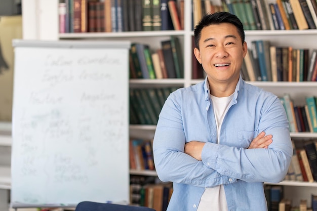 Erfolgreicher koreanischer Lehrer posiert in der Nähe von Whiteboard im Klassenzimmer