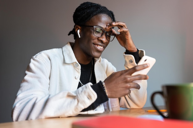 Erfolgreicher lächelnder afroamerikanischer Mann mit Telefon nutzt unterhaltsame mobile Apps oder soziale Medien
