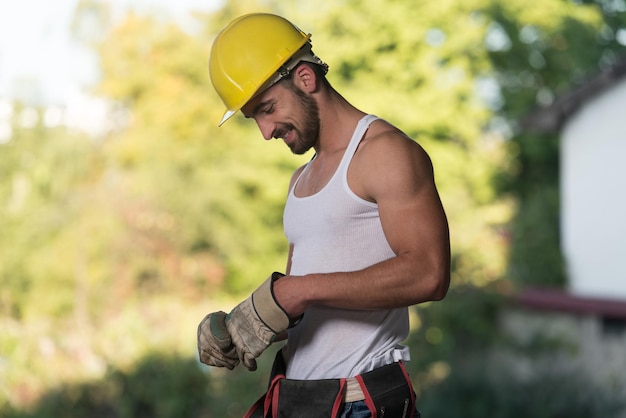 Erfolgreicher männlicher Architekt auf einer Baustelle mit Handschuhen hebt ab