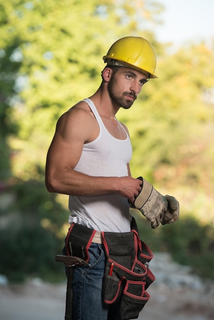 Erfolgreicher männlicher Architekt auf einer Baustelle mit Handschuhen hebt ab