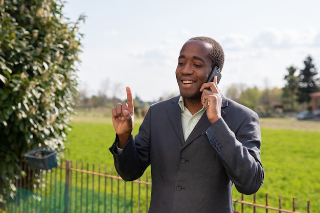 Erfolgreicher positiver afroamerikanischer geschäftsmann telefoniert mit einem kunden.