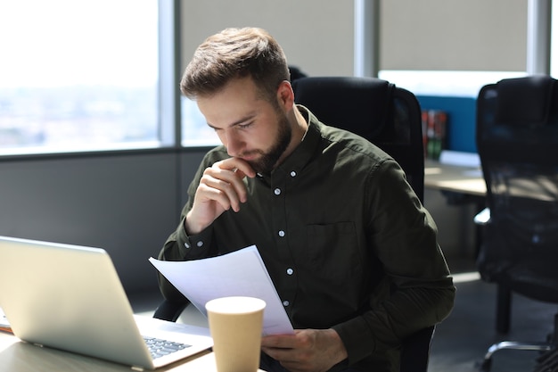 Erfolgreicher Unternehmer studiert Dokumente mit aufmerksamem und konzentriertem Blick.