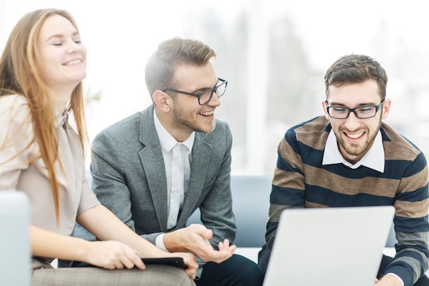 Erfolgreiches Geschäftsteam mit Laptop am Arbeitsplatz bespricht Arbeitsfragen