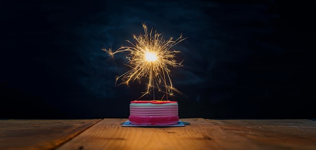 Erfolgsfeierkonzept Der Kuchen auf dem Tisch hat ein Feuerwerk, das das Licht beleuchtet und toll aussieht