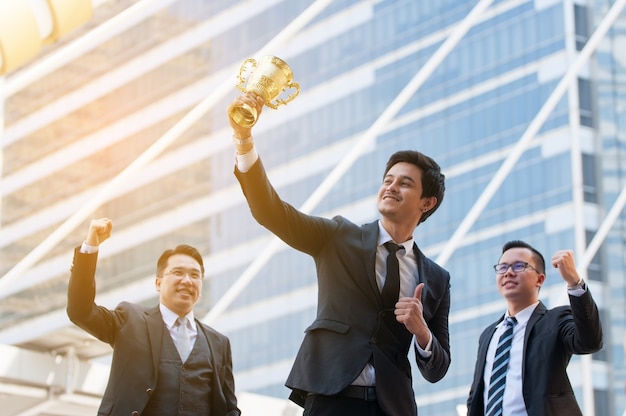 Erfolgsgeschäftsmann, der goldene Trophäenschale hält