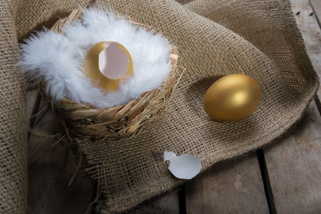 Erfolgssymbol oder fröhliches Ostern-Konzept. Leeres gebrochenes großes goldenes Ei auf einer rustikalen hölzernen natürlichen Tabelle