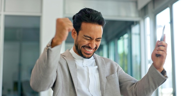 Erfolgstelefon und Gewinner mit Geschäftsmann im Büro und Feier für Geschäftswachstum und Börsenziel. Wow-Ziele und gute Nachrichten mit der Faust des Mitarbeiters für Erfolg, Zukunft und Verkauf