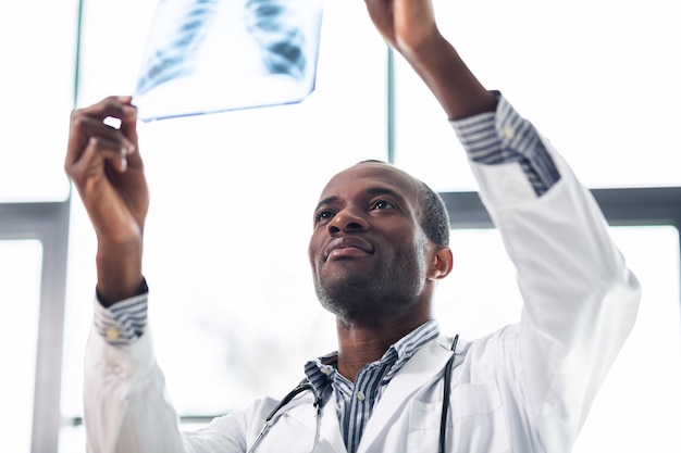 Erfreulicher medizinischer Arbeiter, der beim Betrachten des Röntgenbildes die Arme hebt