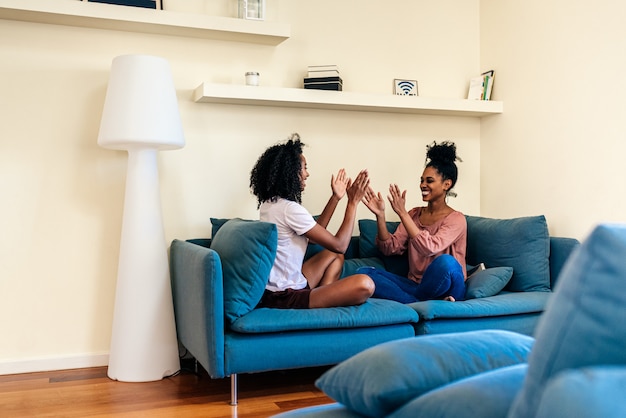 Erfreute frauen hatten klatschspiel auf dem sofa