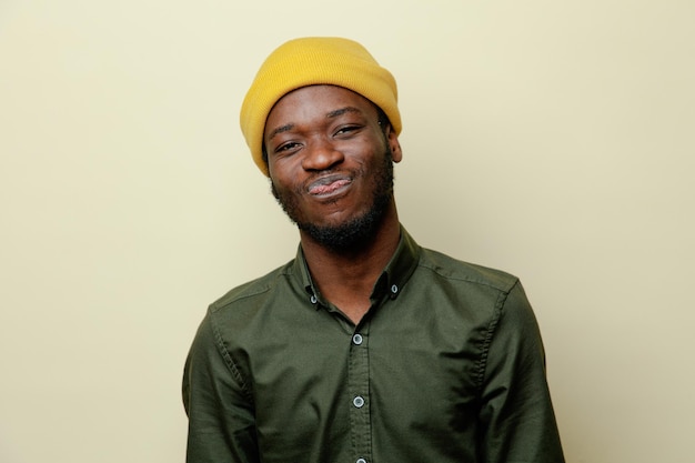 Erfreuter junger afrikanisch-amerikanischer Mann mit Hut, der ein grünes Hemd auf weißem Hintergrund trägt