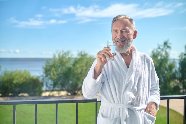 Erfreuter Urlauber, der ein Glas Wasser trinkt