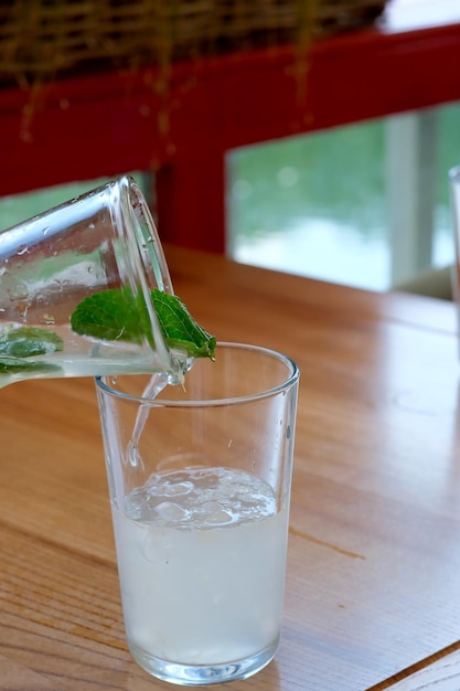 Erfrischende Limonade mit Minzblättern und Eis auf einem Cafétisch an einem sonnigen Sommertag