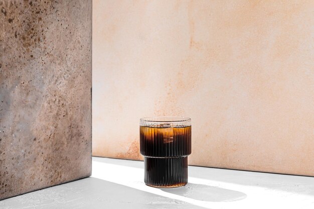 Erfrischender eiskalter schwarzer Kaffee in einem Glas in einem Lichtstrahl mit Kopierraum