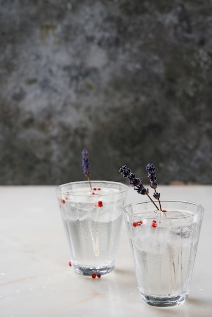 Erfrischender Gin-Tonic-Cocktail mit Kräutern, Gewürzen und Eis über dem Marmorschreibtisch. Selektiver Fokus