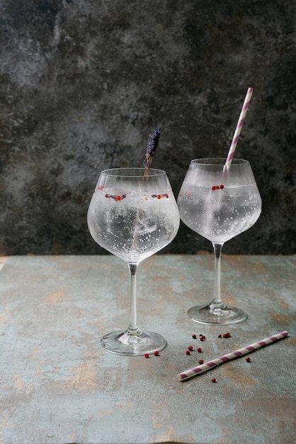 Erfrischender Gin-Tonic-Cocktail mit Stroh, Kräutern, Gewürzen und Eis