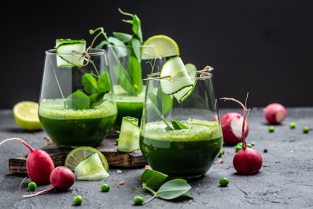 Erfrischender Grünkohl-Gurken-Smoothie in einem Glas auf Betonhintergrund Detox-Smoothie-Grün, frische Erbsen, Gurke, Rettich, Spinat und Limette