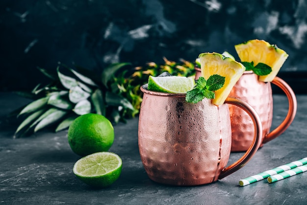 Erfrischender Iced Cold Moscow Mule Cocktail mit Limette und Ananas auf dunklem Hintergrund