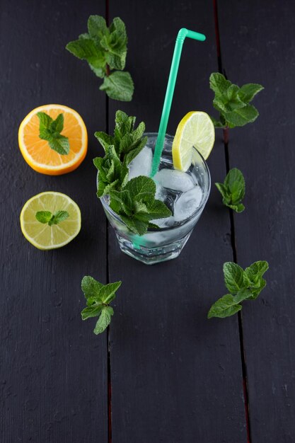Erfrischender kalter Cocktail im Frühling oder Sommer. Glas Cocktail mit Minze und Zitrusfrüchten auf schwarzem Hintergrund. Nahaufnahme