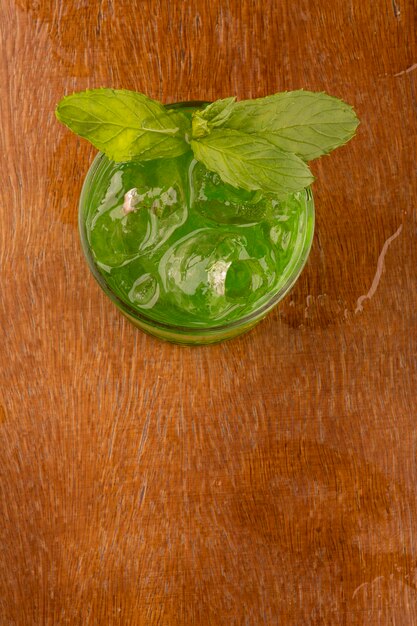 Erfrischender minzgrüner Cocktail mit Eiswürfeln von oben auf Holztisch