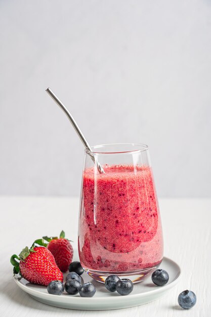 Erfrischender Smoothie aus pürierten süßen roten Erdbeeren und Blaubeeren im Trinkglas serviert