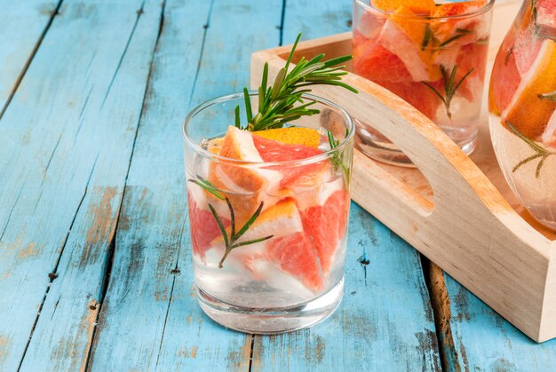 Erfrischender Sommer-Entgiftungscocktail aus Grapefruit und Rosmarin, auf rustikalem Holztisch, Kopierraum